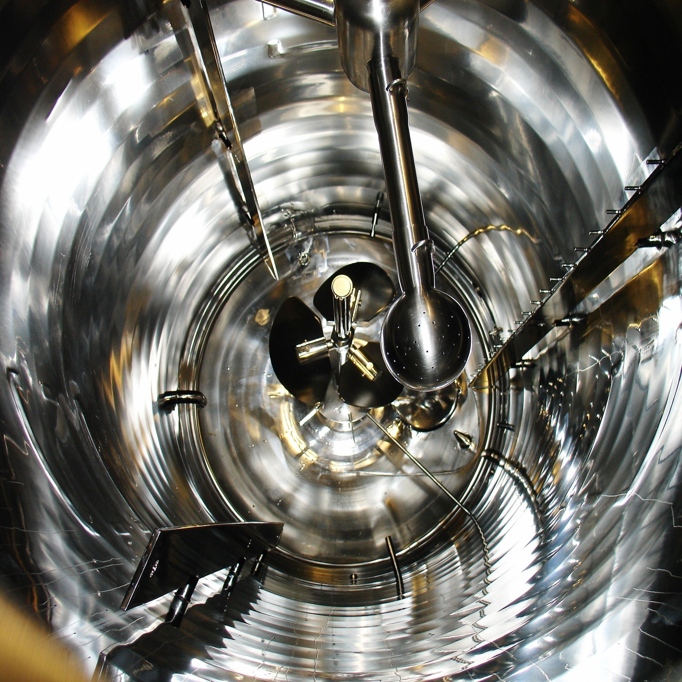 <Looking down on the inside of a clean, polished, mirror finish cylindrical mixing vessel with propellor stirrer. Credit> Fotoluca @ Freeimages