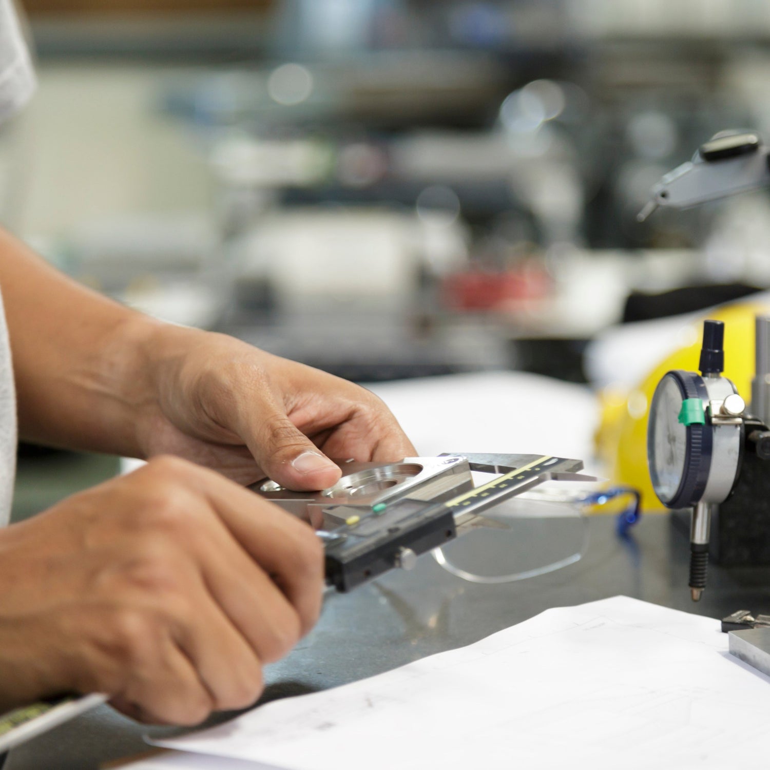 &lt;Man calibrating a pressure gauge on a filling machine with blurred production background using some digital calipers and tubing. Credit&gt; AdobeStock_136338979