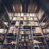 <Close up of racking seven pallet spaces wide and seven spaces high containing trays of bottles with a gap in the middle forming a rectangular arch walkway. Credit> AdobeStock_144478550