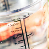 <Close up of a graduated glass analytical beaker containing exactly 1 litre of water with light shining through it. Credit> AdobeStock_215147580