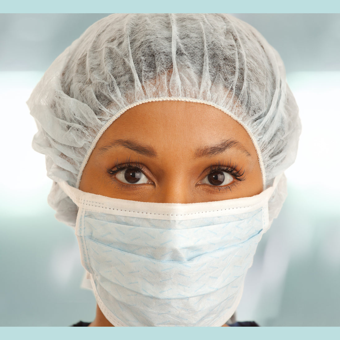 &lt;Female production operator with brown eyes and skin demonstrating the correct way to wear a white hairnet and face mask as per the gowning procedure. Credit&gt; AdobeStock_223463107