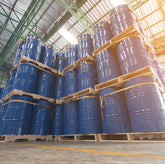 <Delivery of eighteen pallets stacked in rows three high on a concrete warehouse floor each with four 200Kg blue metal drums containing dietary supplement ingredients, behind which is a metal ceiling with sunlight flooding through skylights. Credit> AdobeStock_224567290