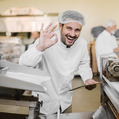 &lt;Male, production team leader, wearing white coat and hairnet, smiling and making an OK symbol with his hand next to a tablet filling machine. Credit&gt; AdobeStock_226047743