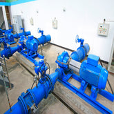 <Several blue water pumps and pipework transporting water around the dietary supplement facility located in a clean white room with concrete floor. Credit> AdobeStock_241267554