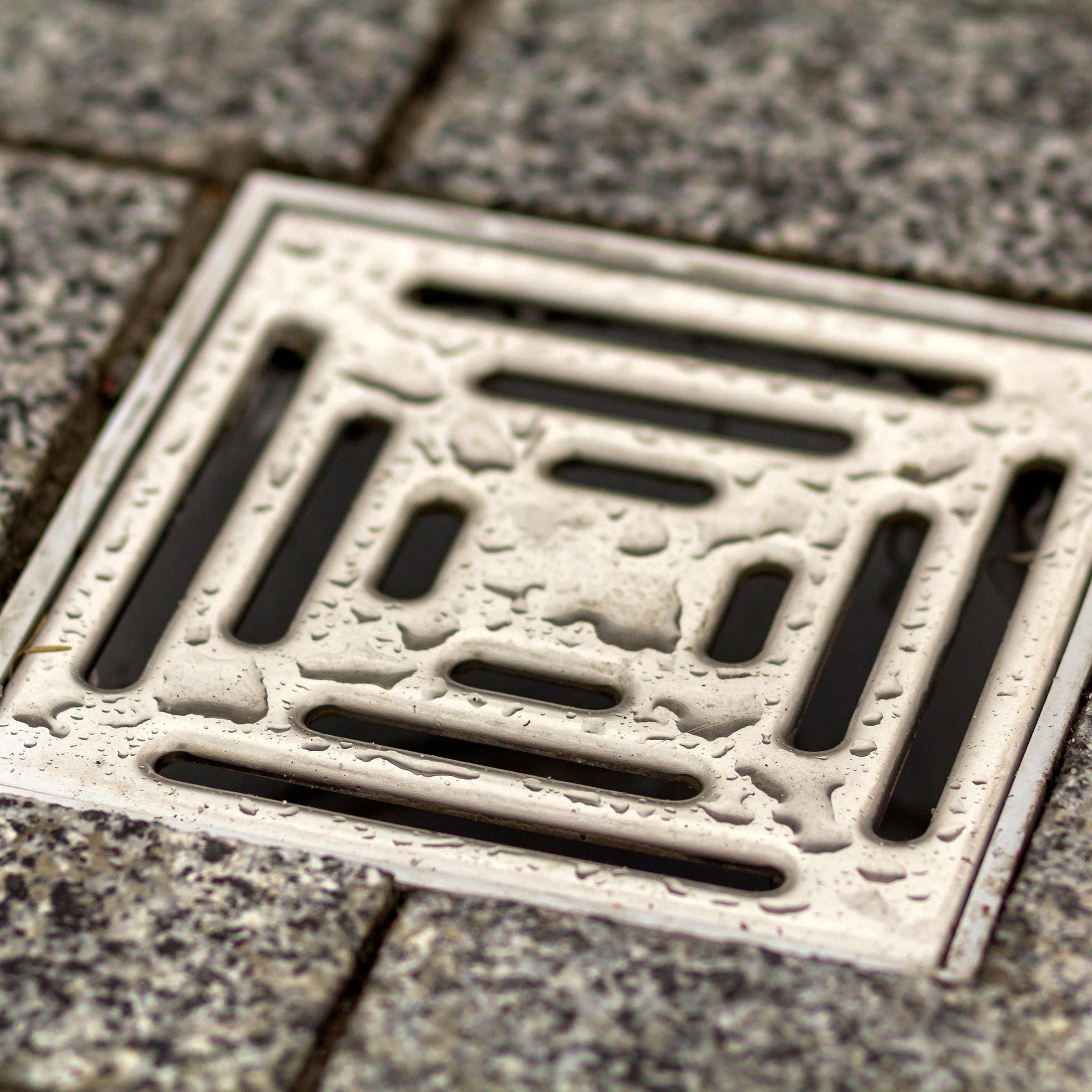 &lt;Square, metal floor drain in a grey stone tiled floor. Credit&gt; AdobeStock_245003730