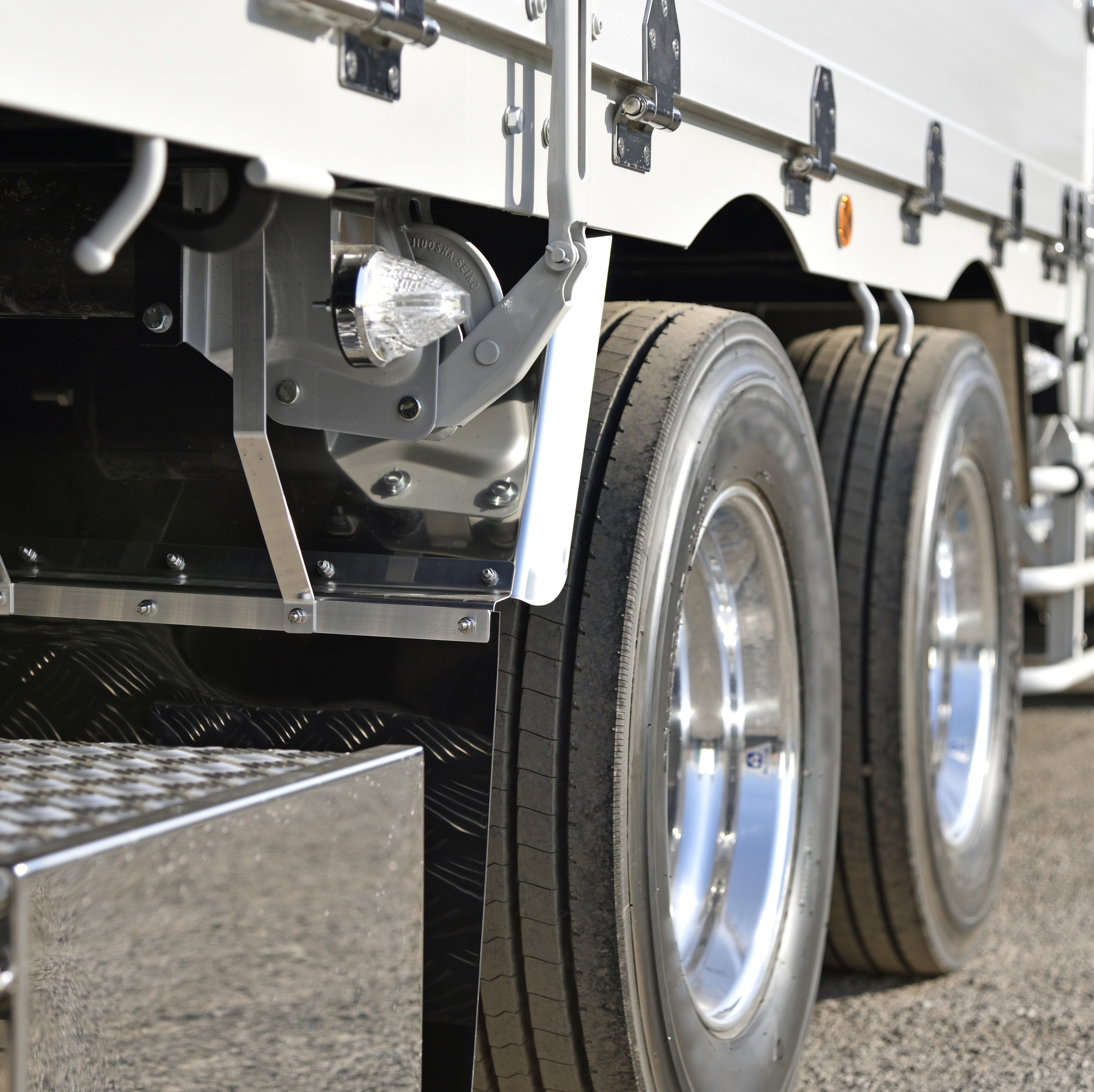 &lt;Middle two chrome wheels, step entry and part of the white container of a lorry in the tarmac yard of a dietary supplement facility to distribute finished product. Credit&gt; AdobeStock_247941076