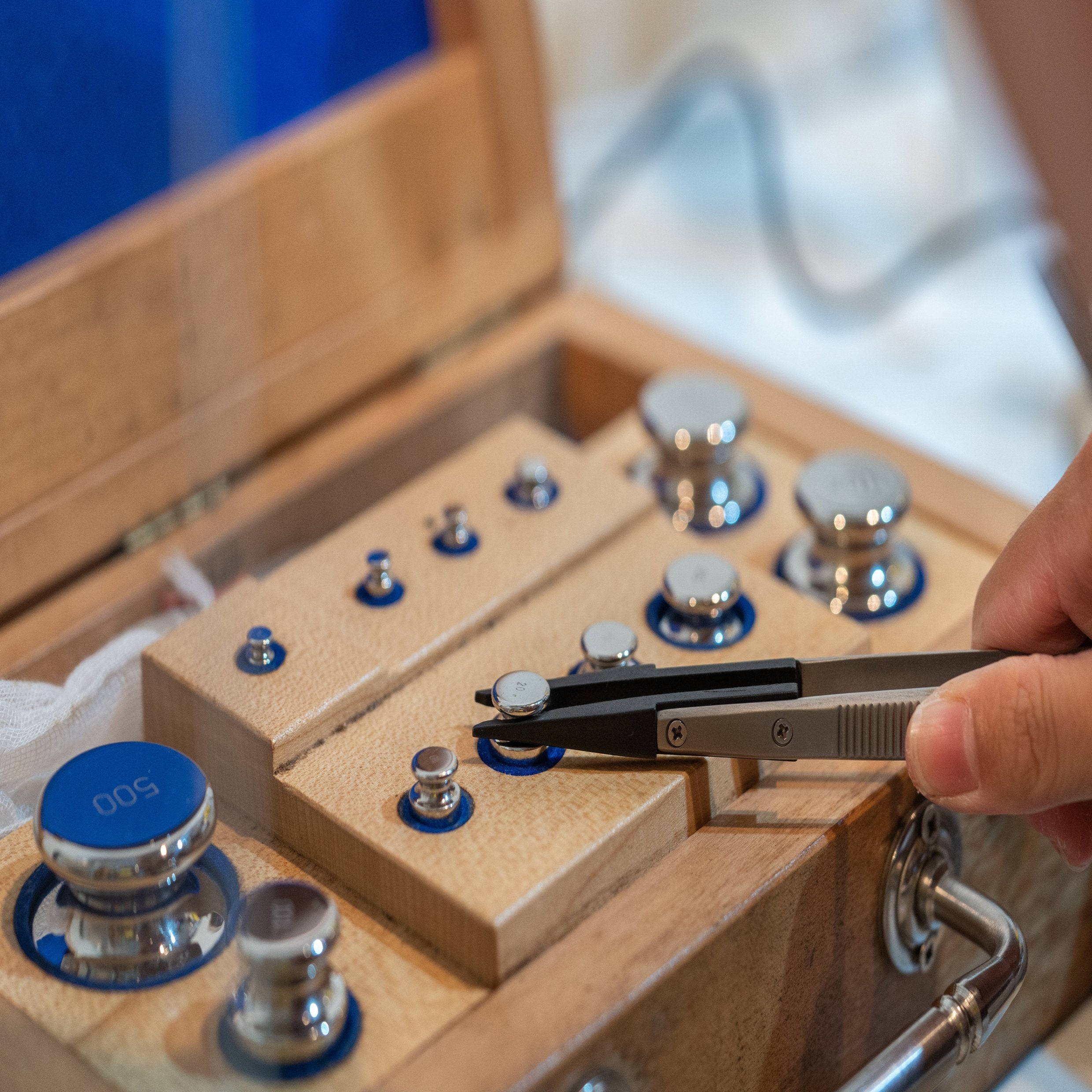 &lt;Lifting a chrome calibration weight, used for calibrating analytical balances, with rubber tipped metal  tweezers from a set of different sized weights in a wooden box. Credit&gt; AdobeStock_274078427