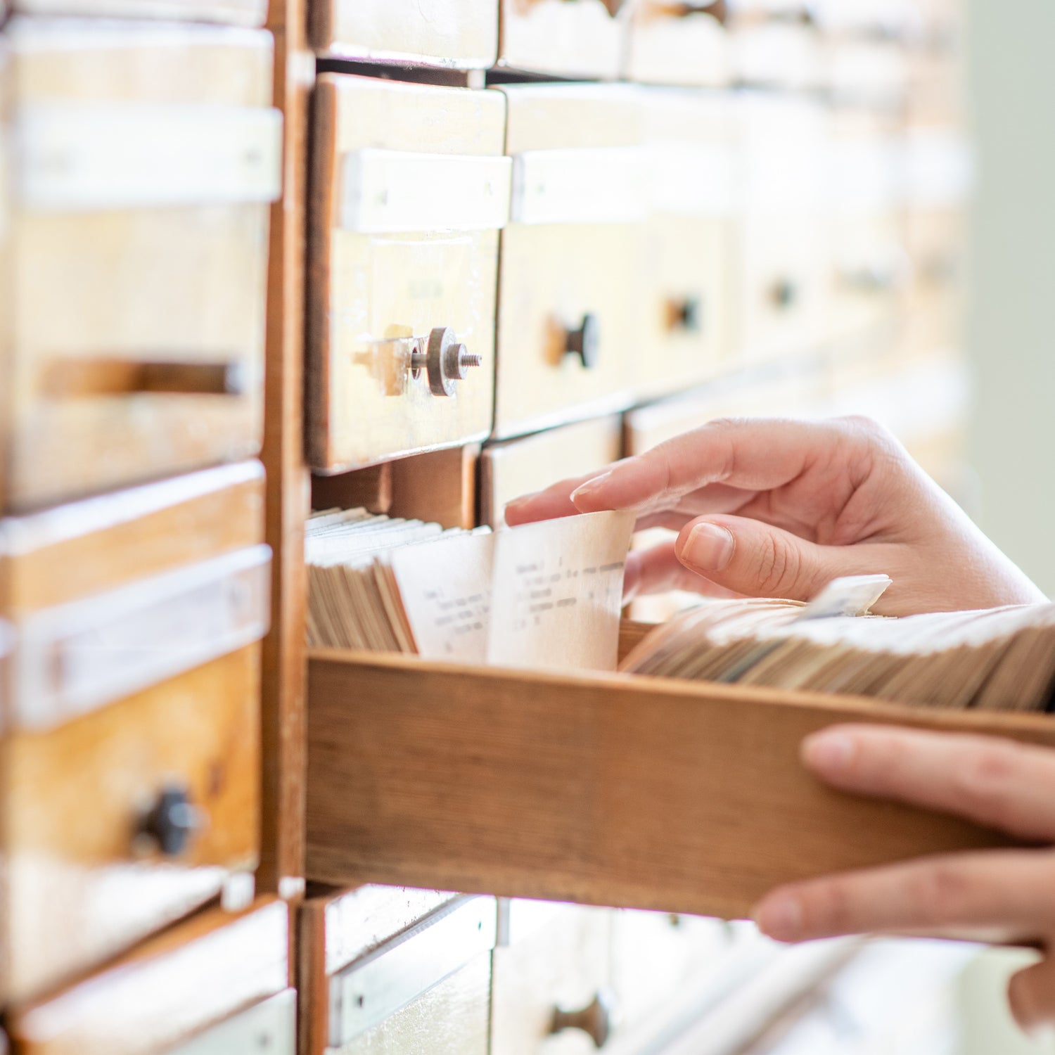 &lt;Female hands searching through hand written records of old customer complaints kept on cards in a wooden box file drawer system. Credit&gt; AdobeStock_284668162