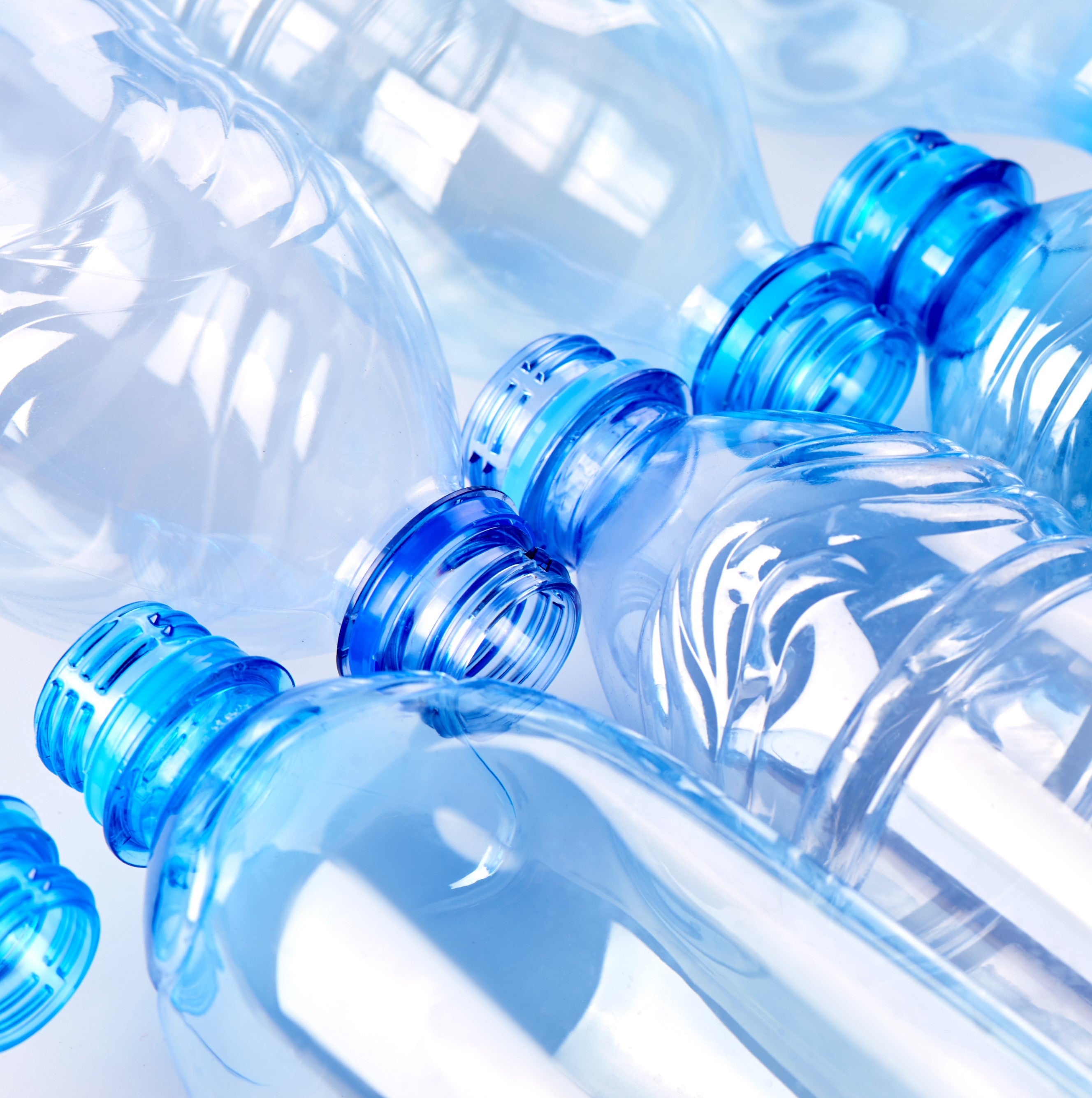 &lt;Two rows of clear, blue plastic bottles lying down in opposite directions top next to top. Credit&gt; AdobeStock_297593696