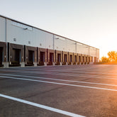 <Tarmac yard of a dietary supplement distribution centre which has 20 painted lanes and entry doors for container lorries. Credit> AdobeStock_315006586