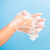 <Picture of two arms against a light blue background creating foam lather as they rub and wash their hands together,. Credit> AdobeStock_345027763