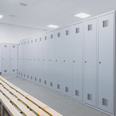 <Clean, well ordered changing area for dietary supplement production staff including grey lockers for personal belongings and wooden benches. Credit> AdobeStock_348001508