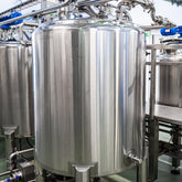 <Several large, cylindrical, shiny stainless steel  mixing tanks and pipework in a dietary supplement manufacturing unit with gantry, grey non slip floor and white ceiling. Credit> AdobeStock_383238064