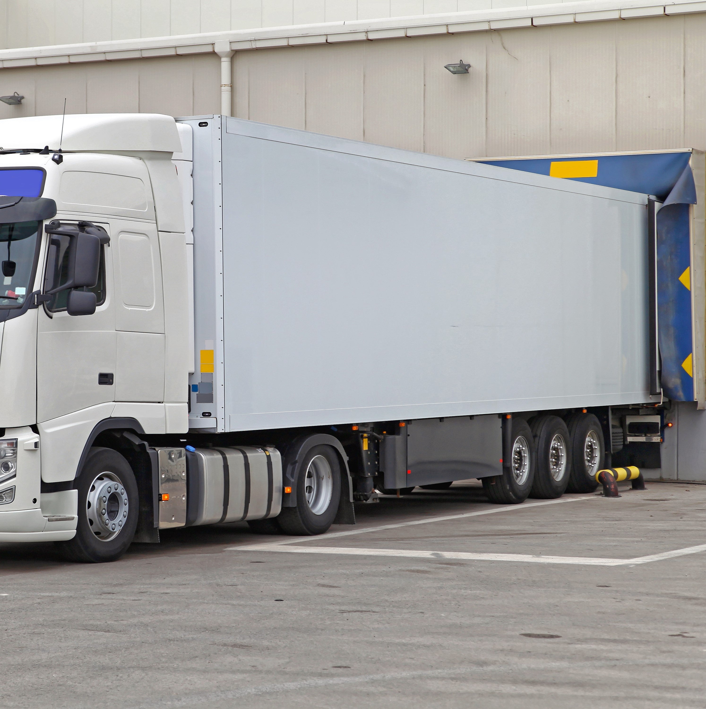 &lt;Large white lorry in the concrete yard of a drug facility reversed up to a dock door in the warehouse to make a delivery. Credit&gt; AdobeStock_403412047