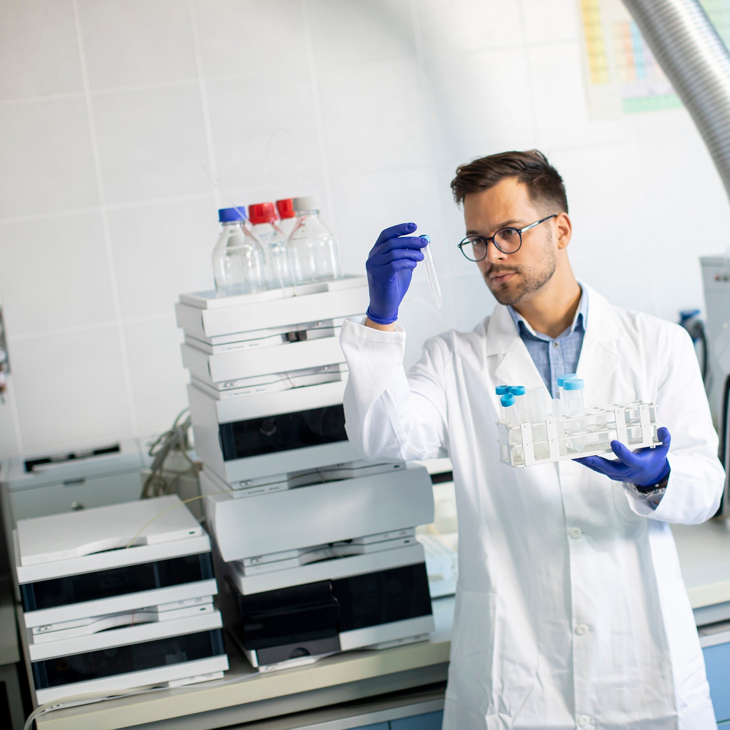 &lt;Male QC Analyst in front of an HPLC looking at a sample in a flask performing the lab tests to determine identity, purity, strength, and composition of the dietary supplement. Credit&gt; AdobeStock_403421068