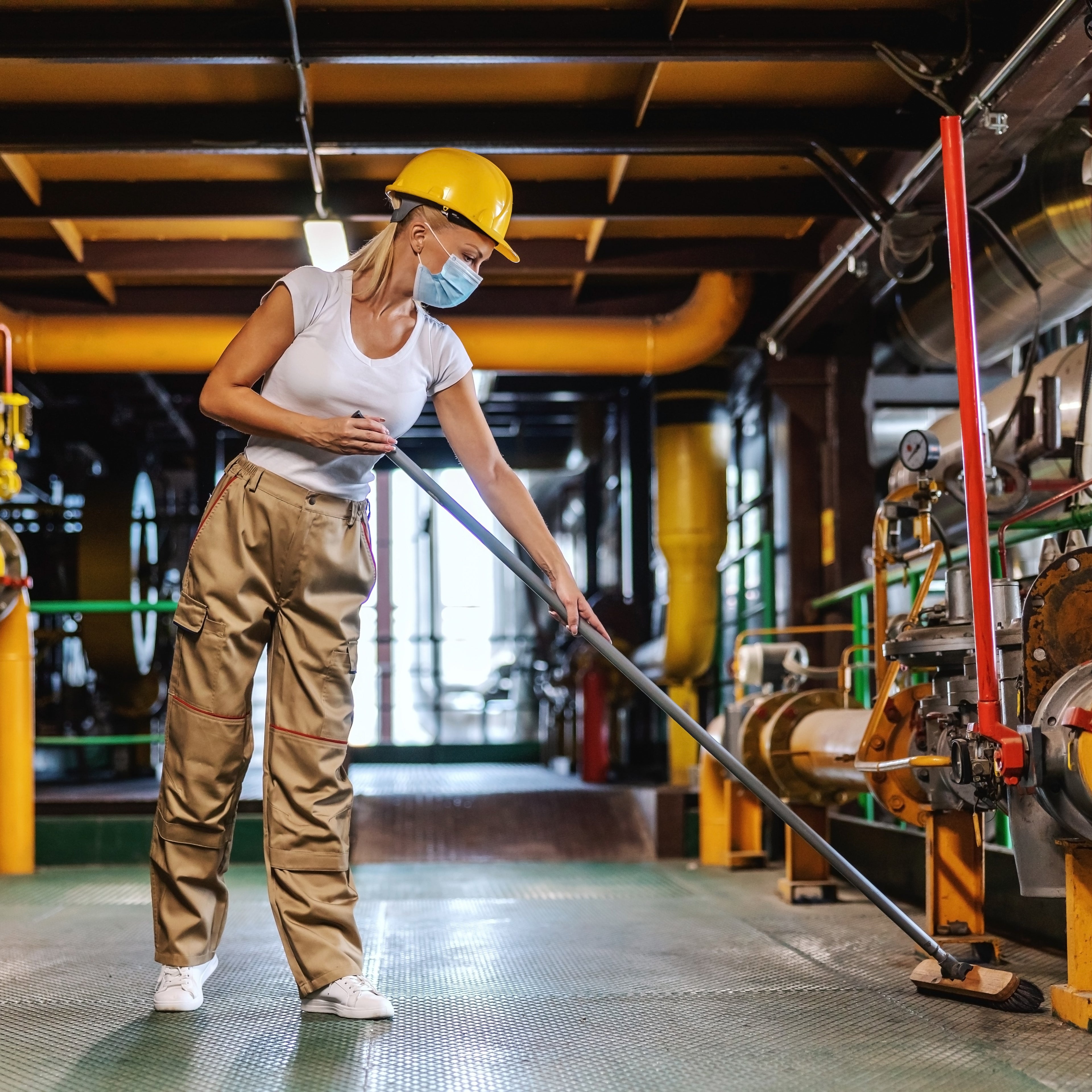 &lt;Female production operator cleaning the metal grid floor of a plant room area with a brush. Credit&gt; AdobeStock_403490907