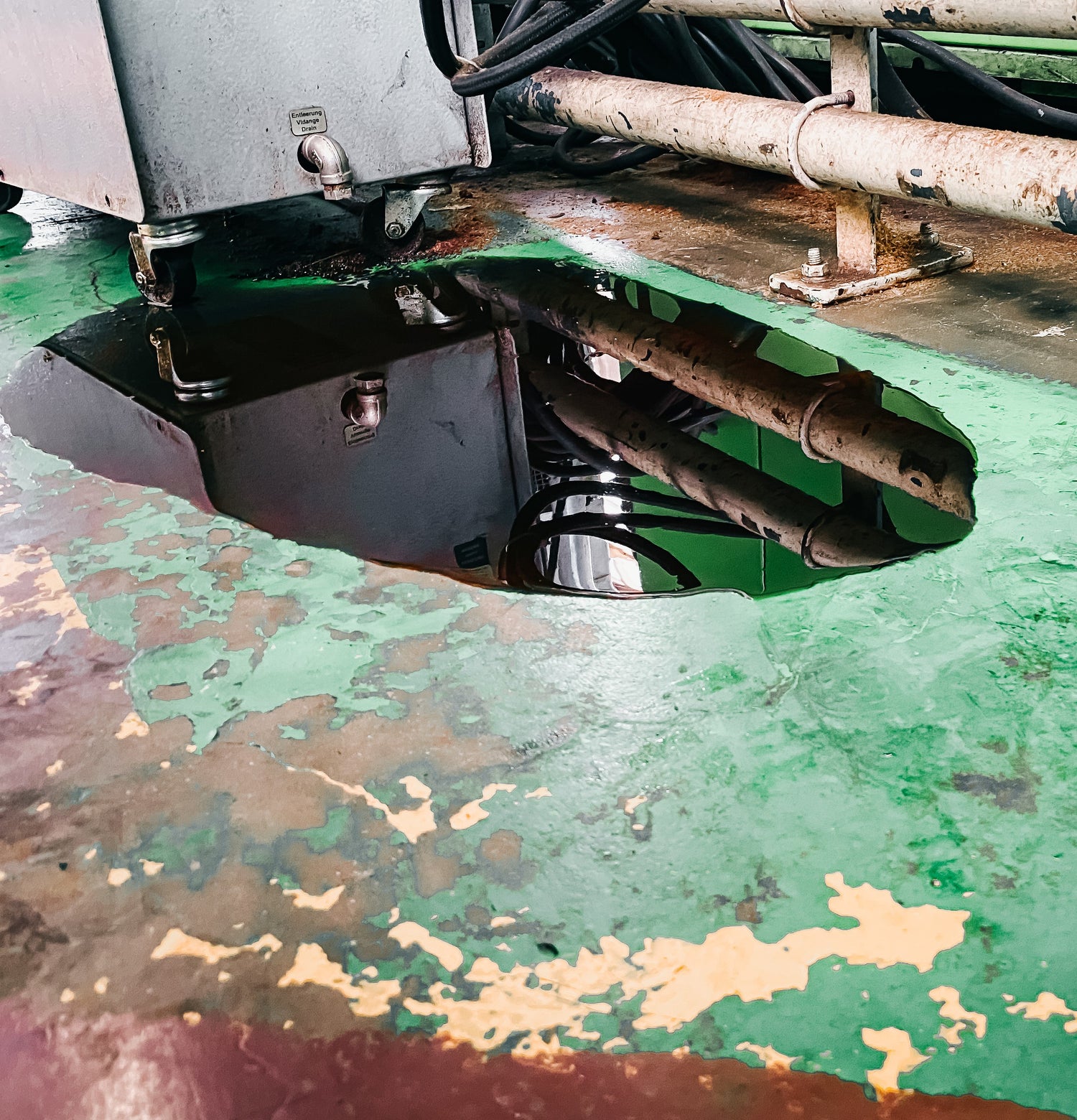 &lt;Oil leaking from an old compressor onto a floor in a poor state of repair with paint peeling off and dirty. Credit&gt; AdobeStock_403818552