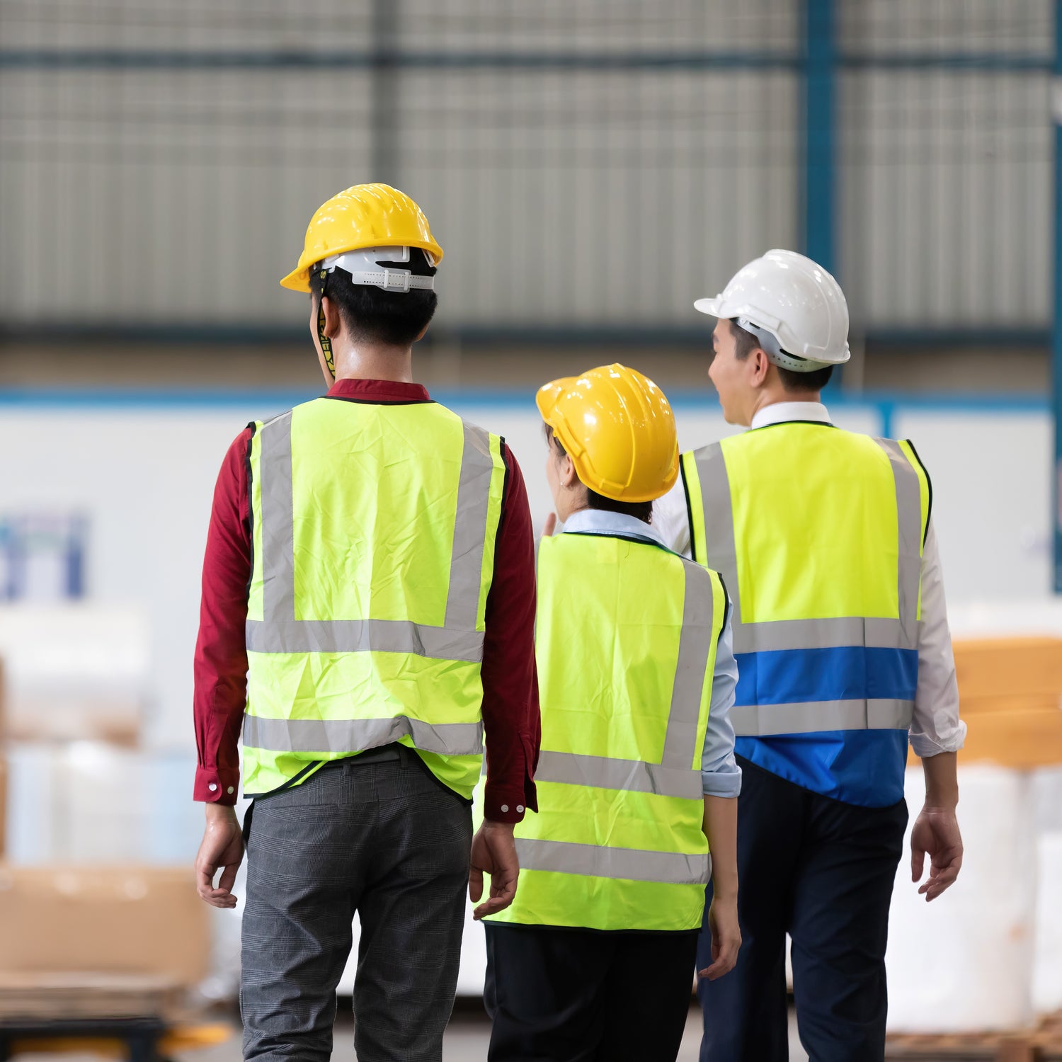 &lt;Senior warehouse manager on a walkaround with two operators, all wearing fluorescent jackets and hard hats, his white, theirs yellow, with their backs to the camera. Credit&gt; AdobeStock_449672578