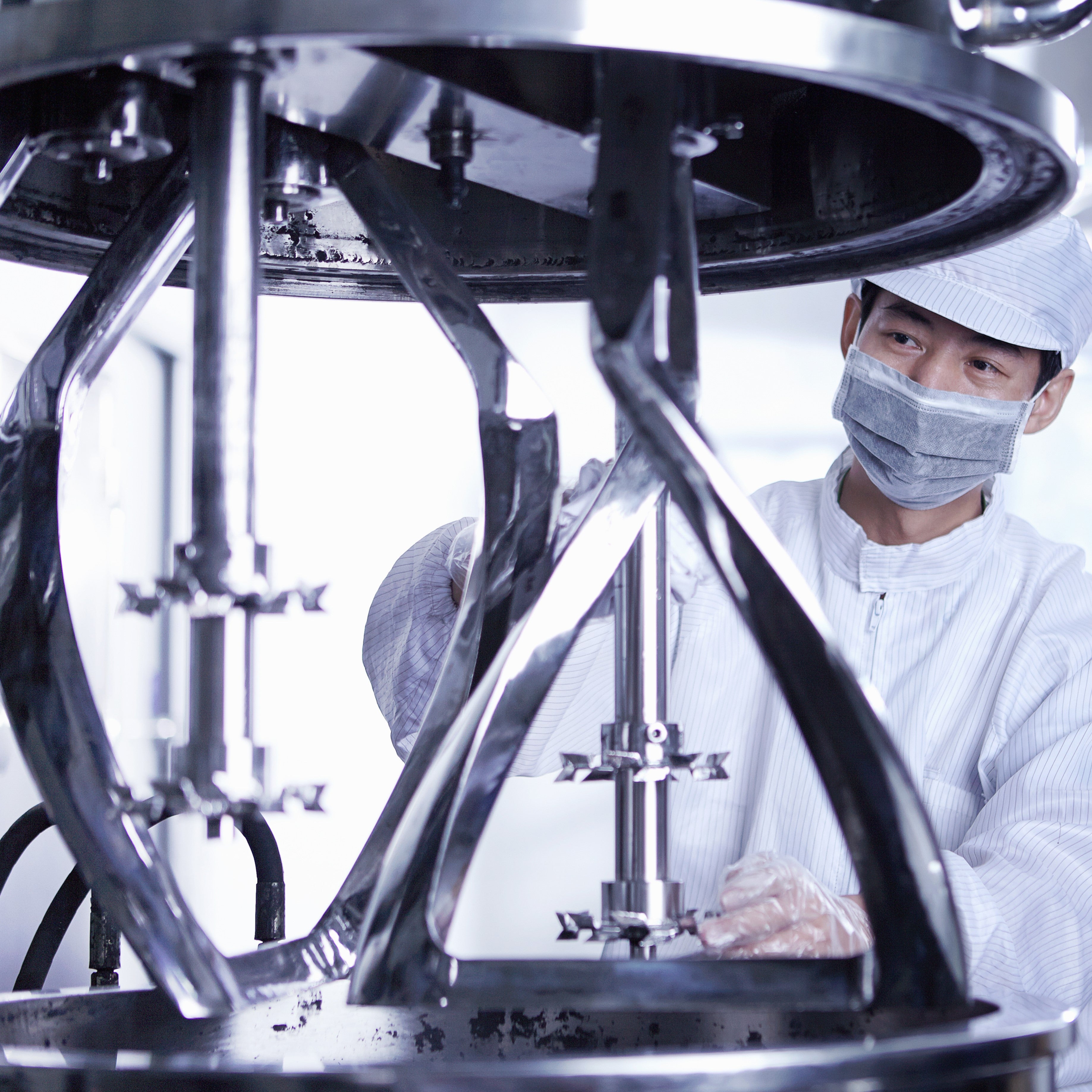 &lt;Male operator stood next to the raised lid of a polished stainless steel mixing tank with attached agitator stirrers. Credit&gt; AdobeStock_456575470