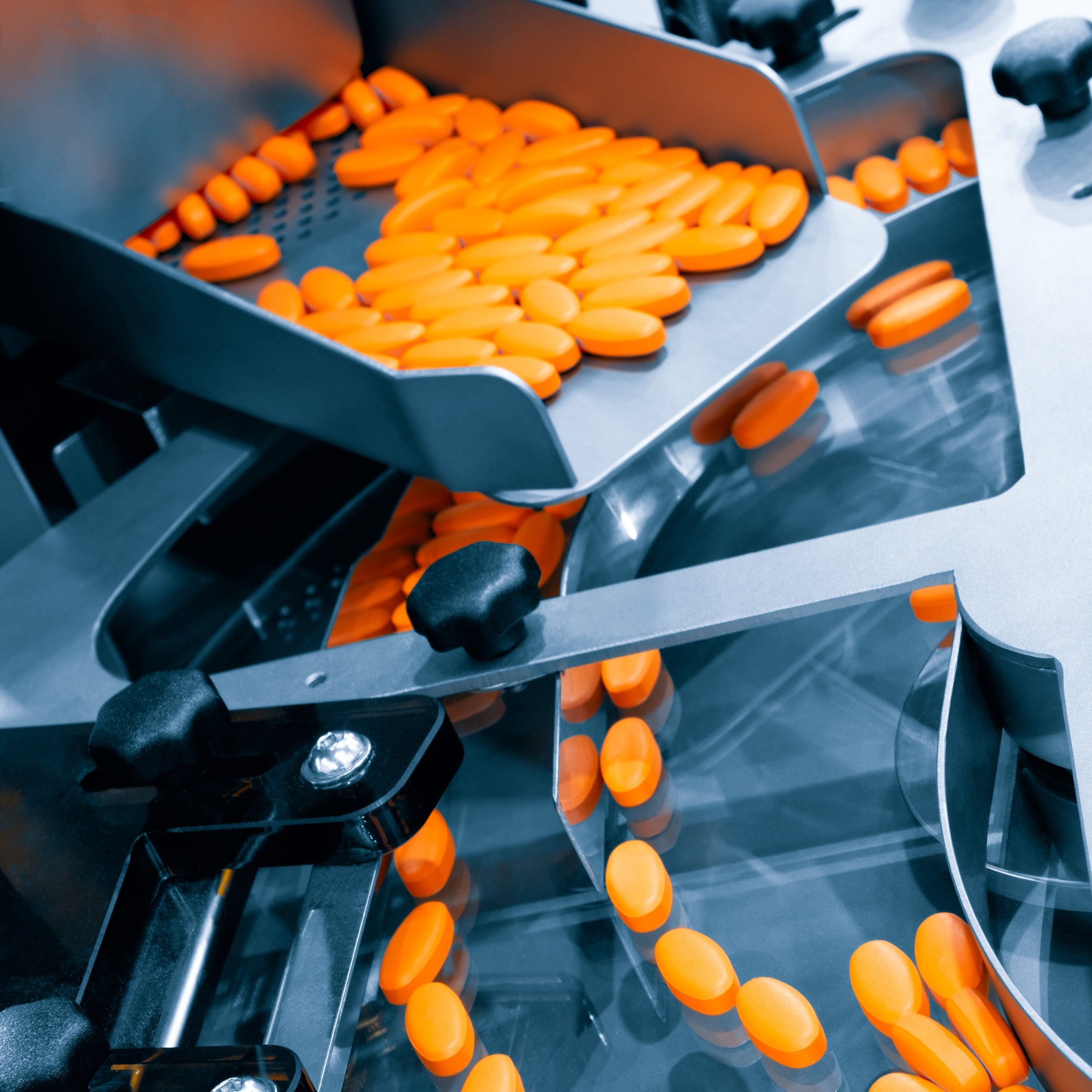 &lt;Yellow dietary supplement tablets moving down a metal chute onto a rotary tablet filling machine to be aligned ready for packing. Credit&gt; AdobeStock_477674087