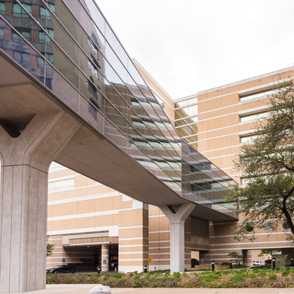 &lt;Concrete and glass bridge walkway between two buildings in a drug facility above a road and garden space. Credit&gt; AdobeStock_523238820