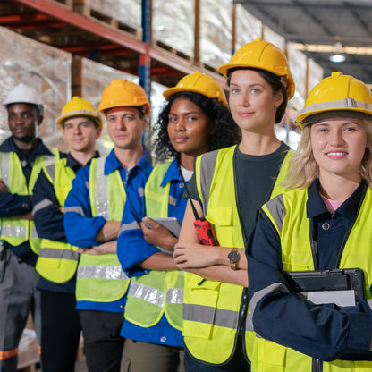 &lt;Six new employees in a line for the camera on an induction site tour in the warehouse wearing yellow fluorescent jackets and hard hats. Credit&gt; AdobeStock_574734269