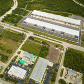 <Overhead photograph of a dietary supplement facility with several buildings, yards, roads, parking lots, and green areas. Credit> AdobeStock_632812255