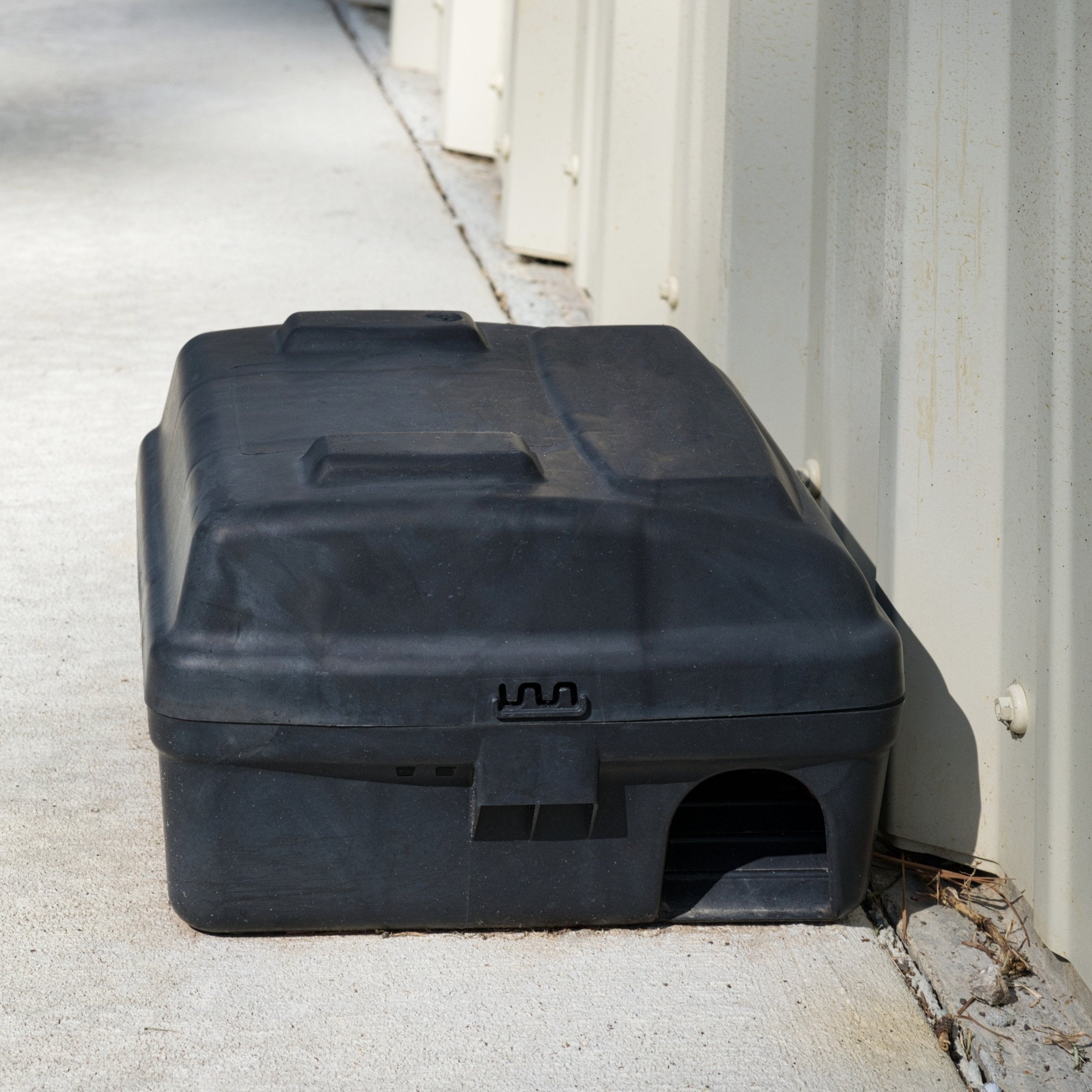 &lt;Black rodent rat or mouse bait station trap box placed along the corrugated metal wall of a warehouse by a pest control specialist. Credit&gt; AdobeStock_735478741