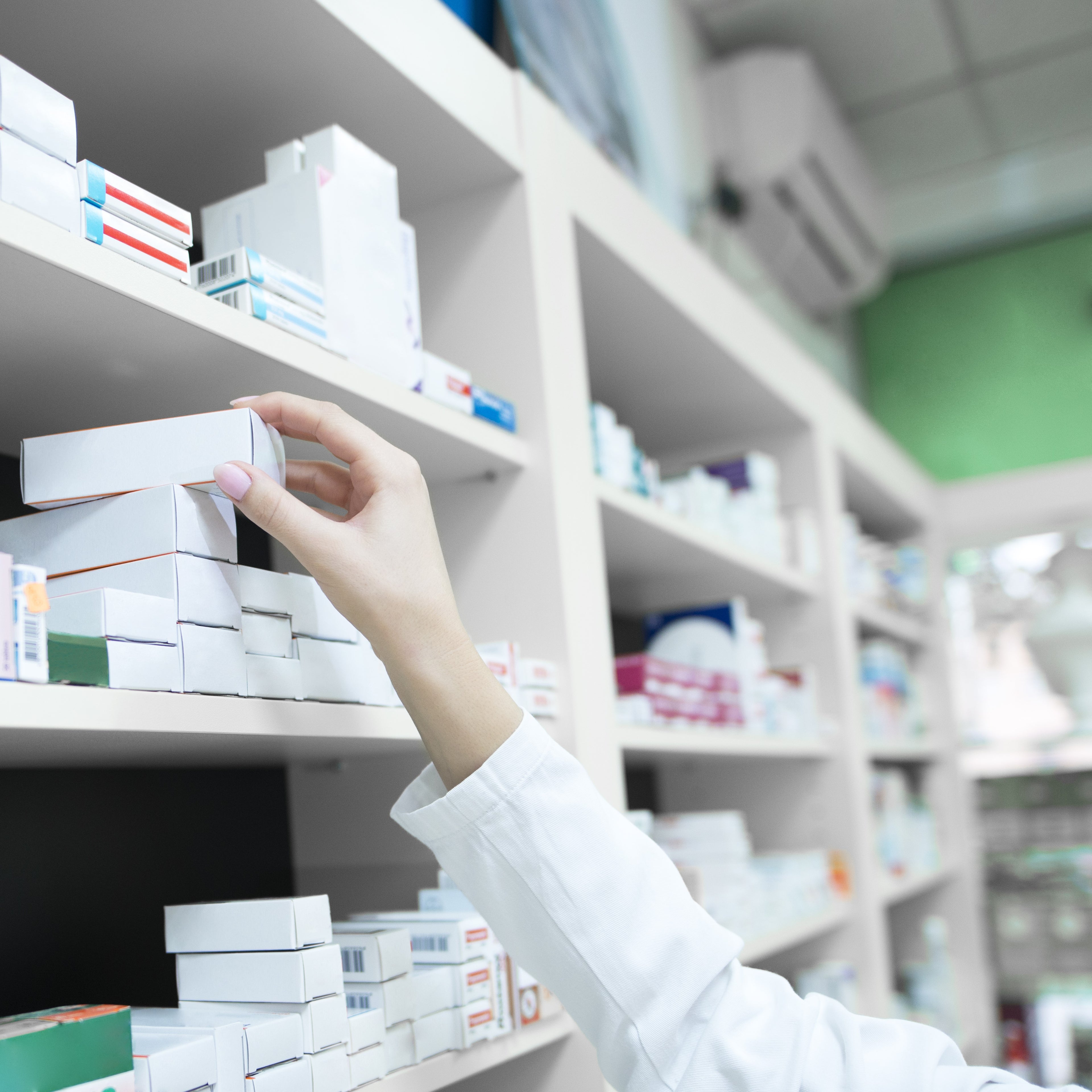 &lt;Close up of female pharmacist arm selecting a cream tube in a carton from the shelf of medicines behind the counter. Credit&gt; Aleksandarlittlewolf @ Freepik