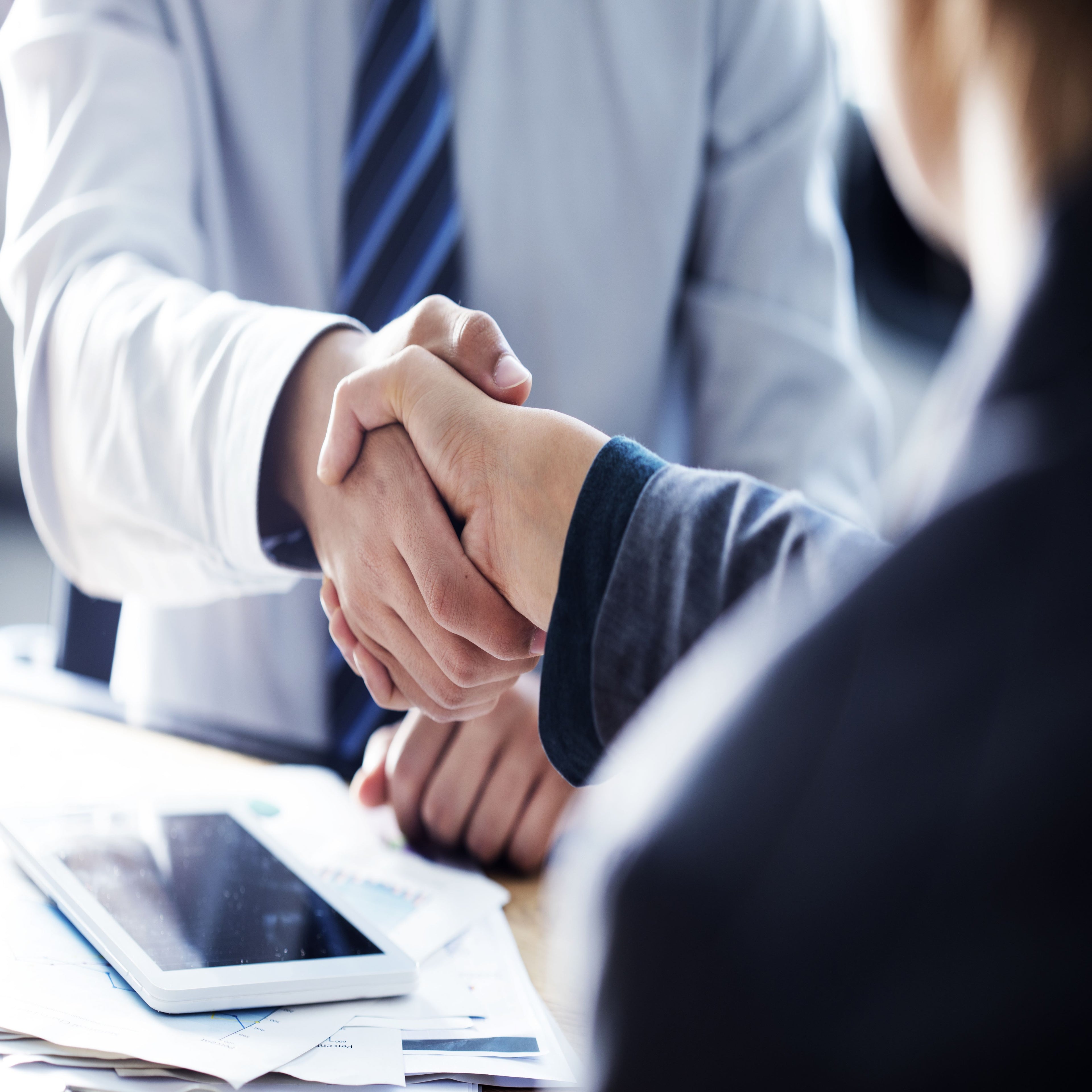 &lt;Two men at a meeting room table shaking hands on an agreed supplier contract. Credit&gt; 101469969 © Sebnem Ragiboglu | Dreamstime.com