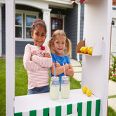 <Two girls selling homemade lemonade from a booth in their front garden. Credit> 71523809 © Monkey Business Images | Dreamstime.com