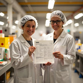 <Two female production operators, wearing white coats and hairnets, holding a completed master manufacturing record, one of the requirements of a batch production record for dietary supplements. Credit> Freepik