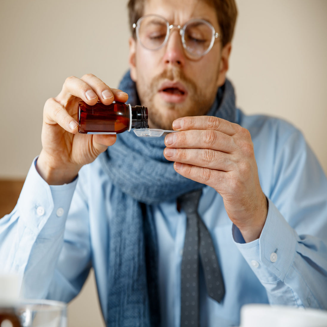 &lt;SIck man at home, looking like sneezing, wearing a scarf, pouring some cough syrup onto a spoon. Credit&gt; Master1305 @ Freepik