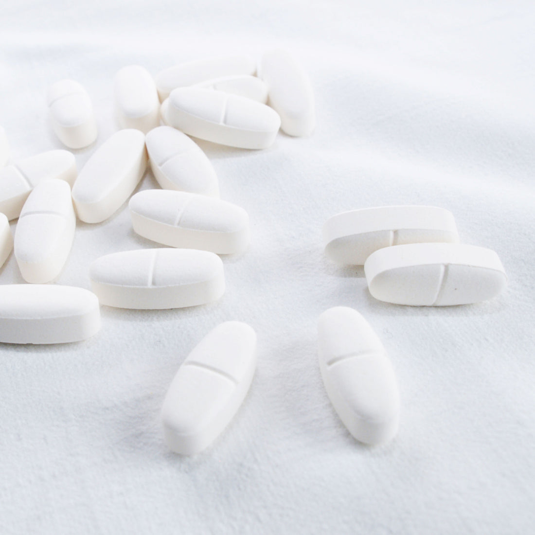 &lt;Approximately 15 white oval 200mg tablets, with half-way break line, spread on a white surface ready for laboratory testing. Credit&gt; 1173911 by leagun @ freeimages